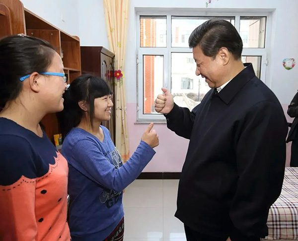 2014年春节前夕，习近平总书记走进内蒙古呼和浩特市儿童福利院，看望住在这里的孩子。听障女孩王雅妮伸出右手弯了弯大拇指，向总书记“说”谢谢，总书记笑容可掬地跟着学。.jpg