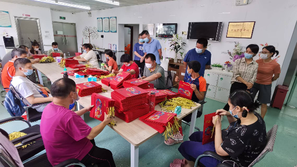 来料加工，会员认真积极做袋子穿绳，工作人员会检查会员完成的手工产品是否合格.jpg