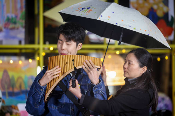 小岱手持排箫立于雨中，以一曲《茶花开了》叩击人心。 