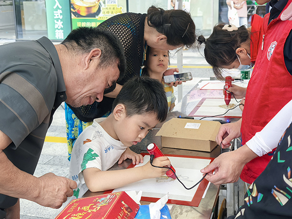 图：小朋友与家长共同体验助残主题糖画创作
