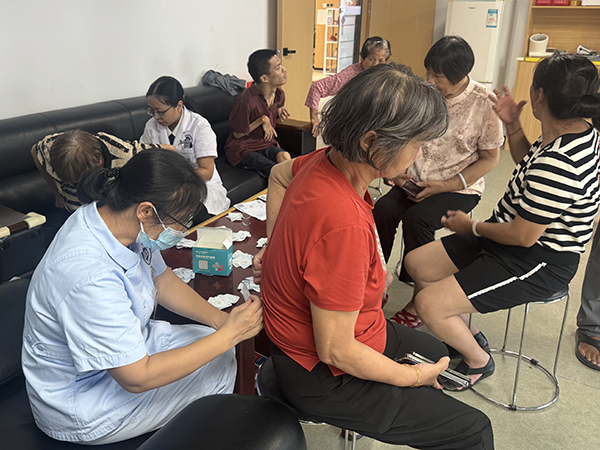 图：社康医护人员为残疾人贴三伏贴