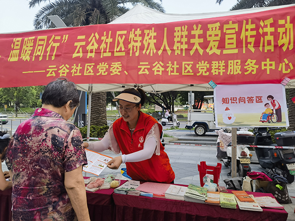 图：工作人员为居民讲解特殊人群关爱政策