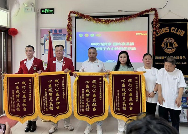 图：残疾人代表以锦旗致谢深圳狮子会并留影