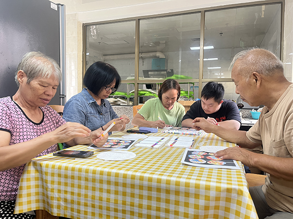图：参与者在专心制作彩绘扇子