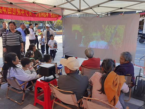 图：居民围坐公益微电影区观看影片