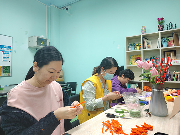 图:工作人员带领残疾人制作扭扭棒花朵 图:工作人员带领残疾人制作扭扭棒花朵