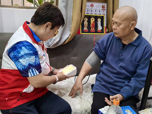 图：退休党员志愿者为辖区独居老人测量血压，分享健康生活技巧
