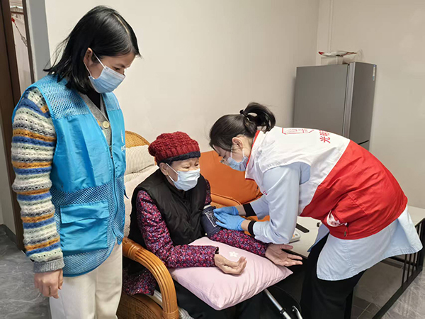图：社康护士志愿者为高龄老人分析血压、血糖的健康值