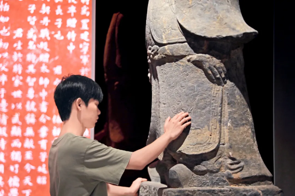 深圳市金石艺术博物馆里，一位视障人士将手掌轻轻贴在一方唐代石刻上