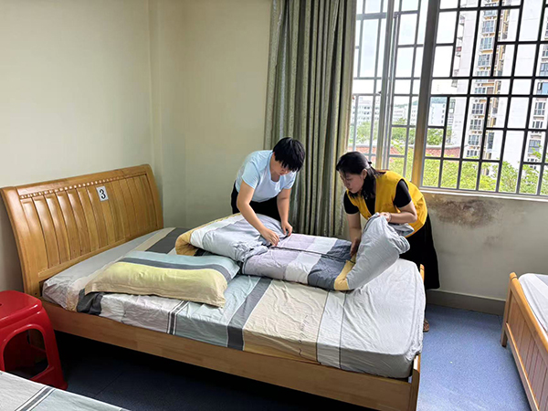 工作人员教授残疾人学习叠被子
