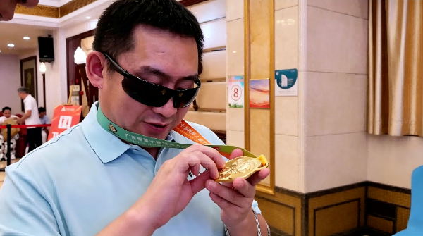 视力残疾运动员金牌选手用指尖细细触摸奖牌上凸起的盲文