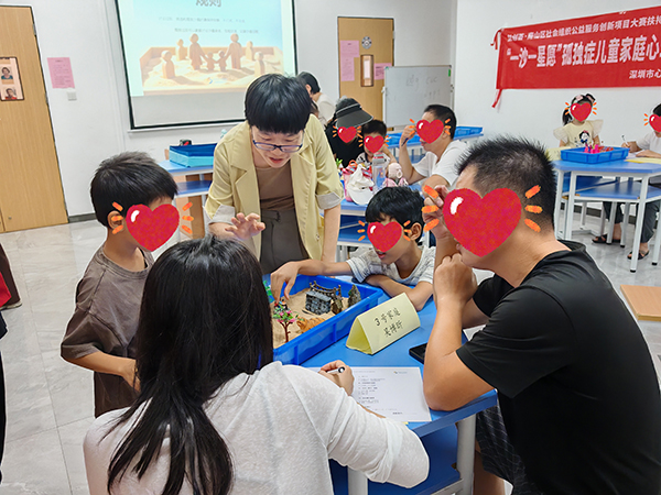 亲子家庭共同摆放沙具老师巡回了解创作情况